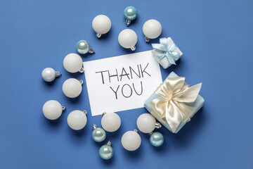 Paper sheet with text THANK YOU, Christmas balls and gifts on blue background