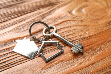 Key with house shape keychain on wooden background