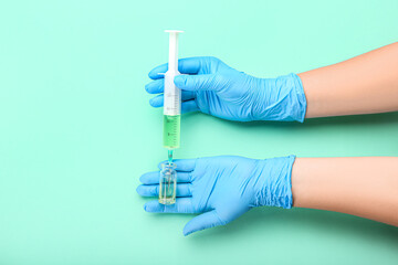 Female doctor with syringe and ampule on color background