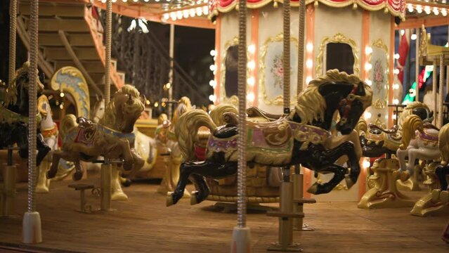 Traditional carousel running in the amusement park on the main square of a city. Close-up of beautifully decorated, running empty seats with vivid lights. High quality 4k footage