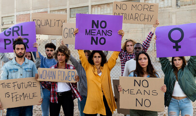 Group of multi-ethnic feminism activist protesting for women empowerment holding banners. No means...