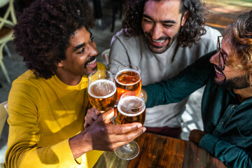 High angle view of happy male friends in a bar enjoying drinks together toasting with beer, having fun.