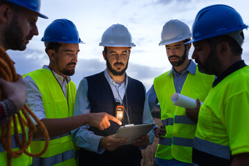 Group of engineers and maintenance workers looking at digital tablet together discussing plans.