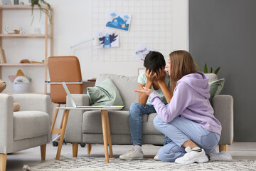 Upset little boy and his mother video chatting with psychologist at home