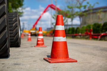 Orange traffic cone in parking lot near hydraulic crane