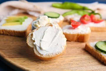 Wooden board of tasty sandwiches with cream cheese, closeup