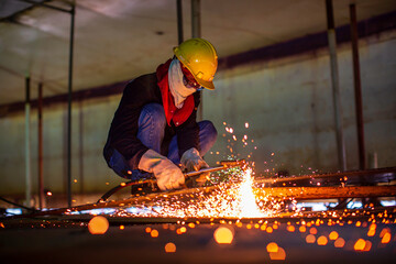 Male worker metal cutting spark on tank bottom steel plate with flash of cutting light close up wear protective gloves and mask