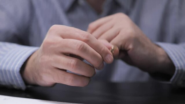 Divorce. The end of the relationship. The man takes off his wedding ring and signs the divorce documents at the lawyer's office.
