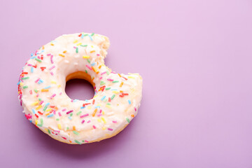 Tasty bitten donut on lilac background