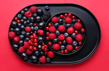 Plates of fresh berries on red background, closeup