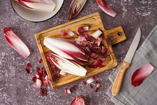 Wooden board with cut red endive on grunge background