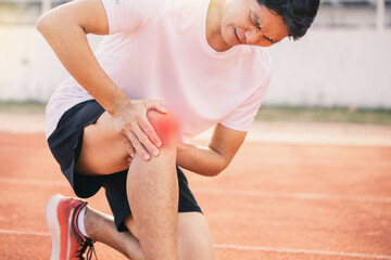 Injured by fitness concept. Man using hands on his knees while working on the street in a park with copy space for text. runner have knee ache due to Runners Knee .