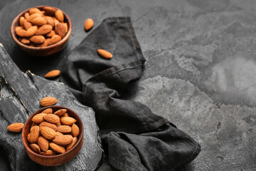 Composition with bowls of tasty almond nuts on dark background