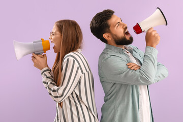 Young couple shouting into megaphones on lilac background
