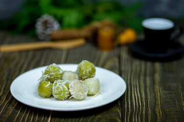 Thai sweets stuffed coconut ball sprinkle with sugar or Kha nom Tom thai language serving on the dark table.