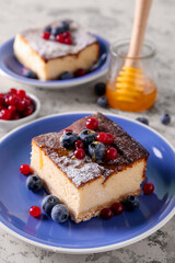 Plate with piece of cottage cheese casserole and berries on light background, closeup