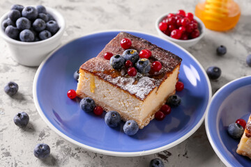 Plate with piece of cottage cheese casserole and berries on light background