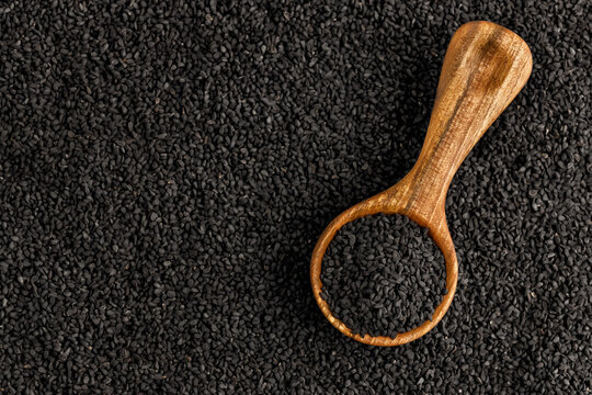 top view of black cumin seeds in scoop and scattered on background