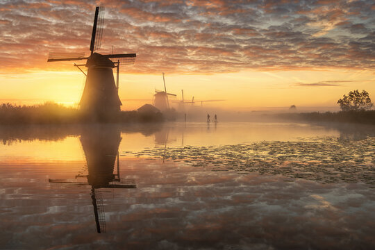 Windm&uuml;hlen am Kinderdijk mit Nebel und Standup Padler bei Sonnenaufgang