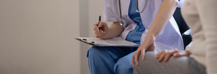 Asian female patient undergoing health check up while female doctor uses stethoscope to check heart rate in nurse, health care concept