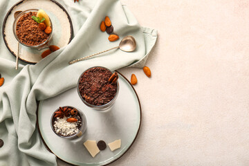 Plates with glasses of delicious chocolate pudding, coconut shavings, cinnamon and anise on white table