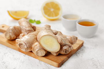 Cutting board with ginger roots on grunge background