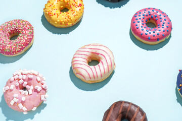 Fototapeta na wymiar Different delicious donuts on blue background