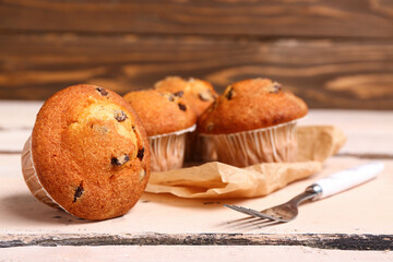 Delicious muffins with chocolate on white wooden table