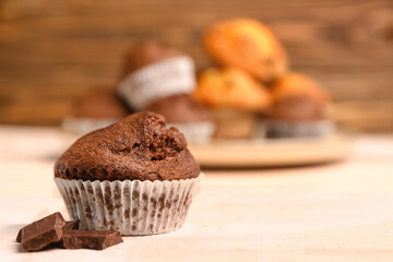Delicious chocolate muffin on white wooden table