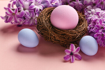 Nest with Easter eggs and hyacinth flowers on pink background, closeup