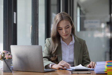 Asian creative businesswoman using laptop computer and business planning, investment and marketing on table in office.
