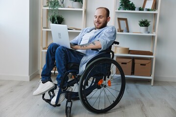 Man in wheelchair freelancer working at laptop at home smile, working online, social networks and startup, copy space, social integration, health concept man with disabilities, real person