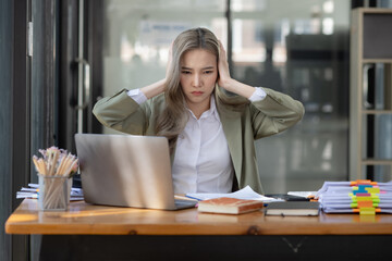 Asian businesswoman are stressed and tired from work sitting at desk in the office, feeling sick at work, stress from work. 