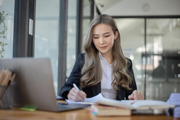 Obraz premium Cheerful asian businesswoman working at table office. 