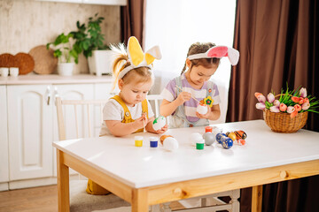 Two children draw Easter eggs in the kitchen. the concept of happiness, easter holiday for children