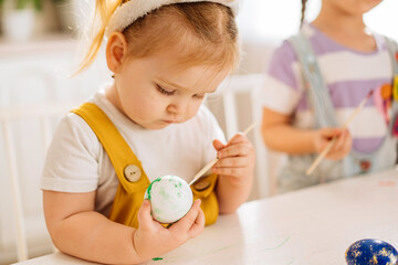 Two happy children draw Easter eggs in a snow-white kitchen. Close-up. the concept of happiness, easter holiday for children