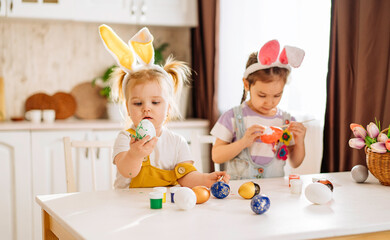 Two happy children fascinatingly draw Easter eggs in a snow-white kitchen. a girl shows an Easter egg. the concept of happiness, easter holiday for children