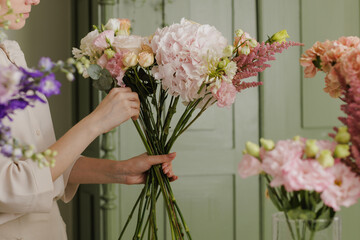 beautiful girl collects a bouquet of flowers in a flower shop