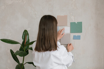 Female architect making mood board on wall in office. 