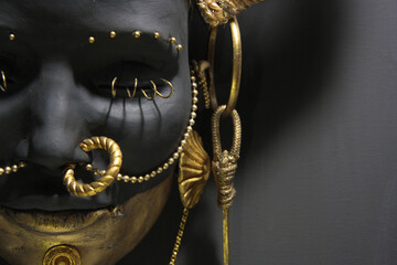Sculpture face detail. Contemporary artwork, female African features. Woman painted in brown color with gold metallic decorations. Large space for text on canvas.