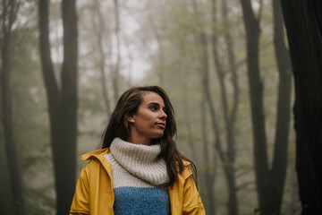 Smiling woman relaxing in nature. Charming and calm young woman breathing fresh air in the mountains.