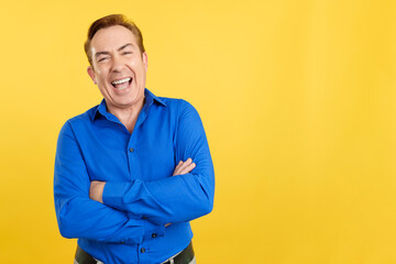 Mature man laughing while standing with arms crossed