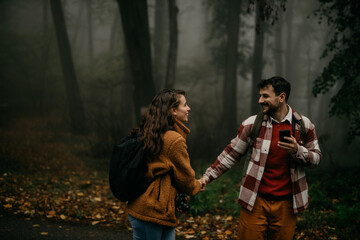 People holding hands and hiking - happy hiker couple trekking as part of healthy lifestyle outdoors activity. Young Caucasian couple walking in nature on a cold day