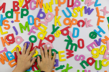 Young girl's hands sorting Alphabet magnets on whiteboard