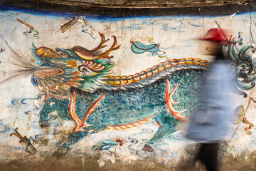 blurred motion people in front of Chinese dragon painting wall.