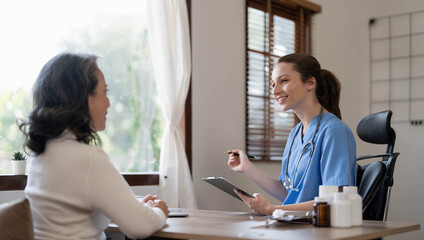 Asian Female Doctor examining and taking note on checklist paper with female patients in medical room.