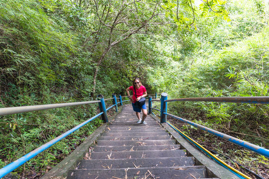 woman hiker smiling and climbing stairs at mountain peak
