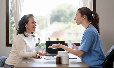 Asian Female Doctor examining and taking note on checklist paper with female patients in medical room.