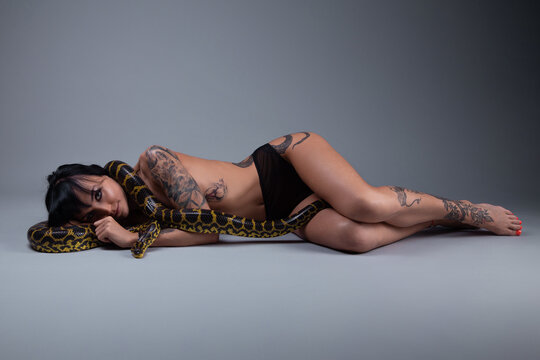 Image of the topless woman in the panties lying on the floor with anaconda