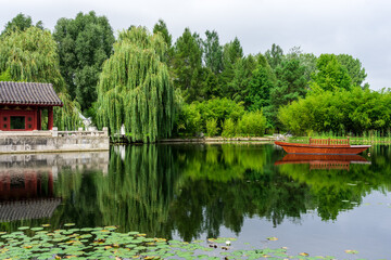 Fototapeta na wymiar Wooden boat and Chinese pagoda by the lake. Summer landscape.